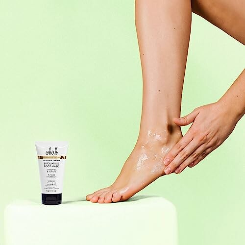 Person applying cream to foot next to a tube of exfoliating foot mask.